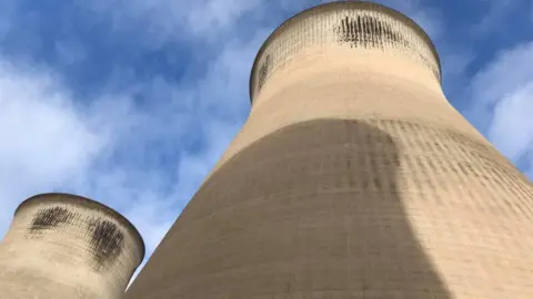 Close-up view of large natural-draft concrete cooling towers against a blue sky